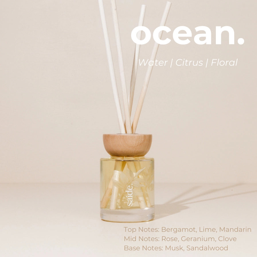 Reed diffuser with wooden base and glass container on a beige background, labeled 'ocean'.