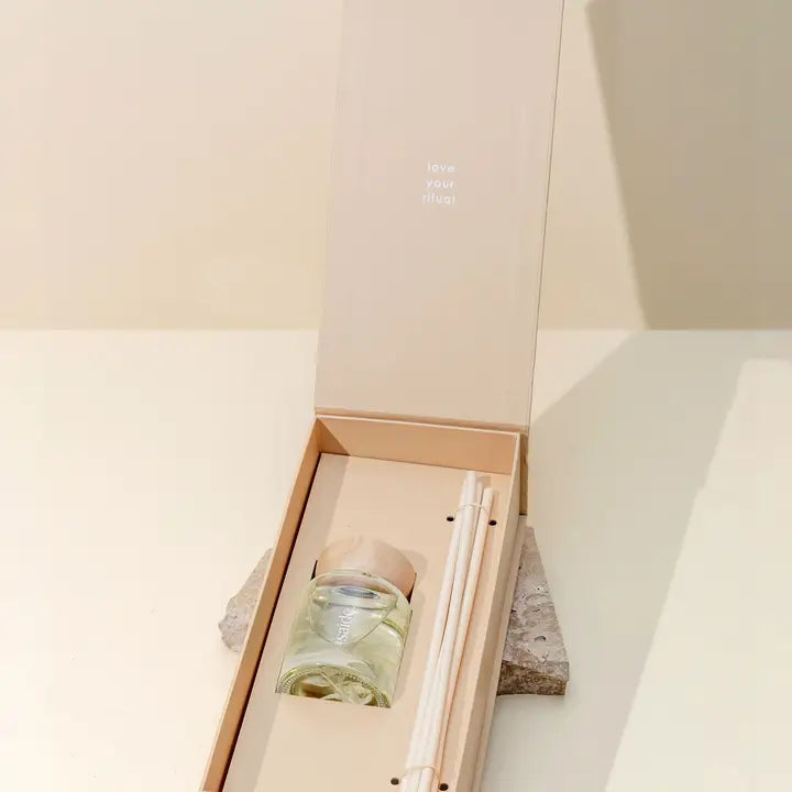 Glass bottle with a straw in a box on a light wooden surface