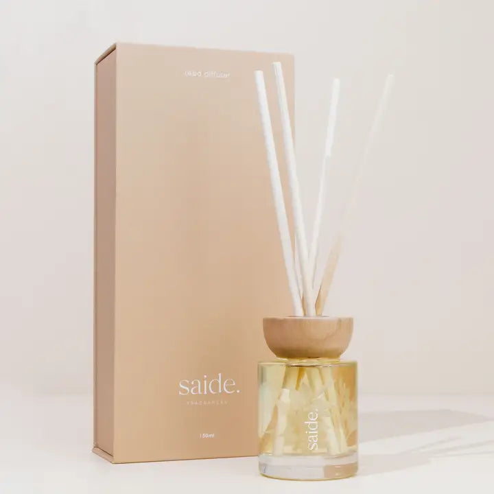 Diffuser with wooden base and white sticks next to a beige box on a light background