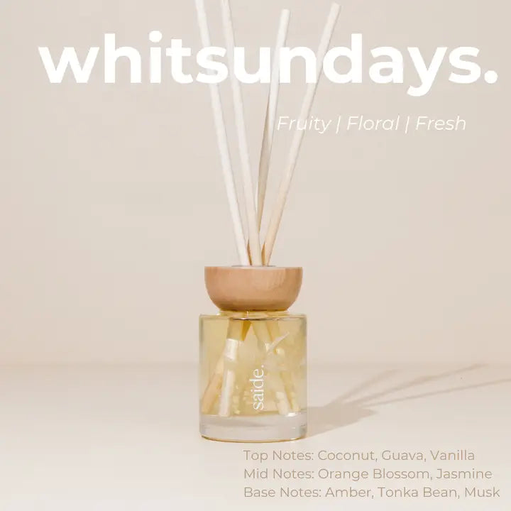 Scented diffuser bottle with wooden top on a beige background, featuring the brand 'whitsundays'.