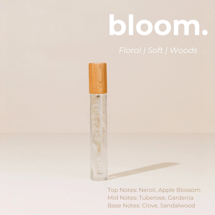 Vial of perfume with wooden cap on a beige background, featuring the brand 'bloom'.