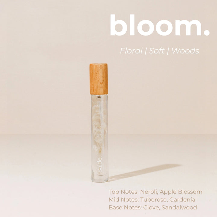 Vial of perfume with wooden cap on a beige background, featuring the brand 'bloom'.