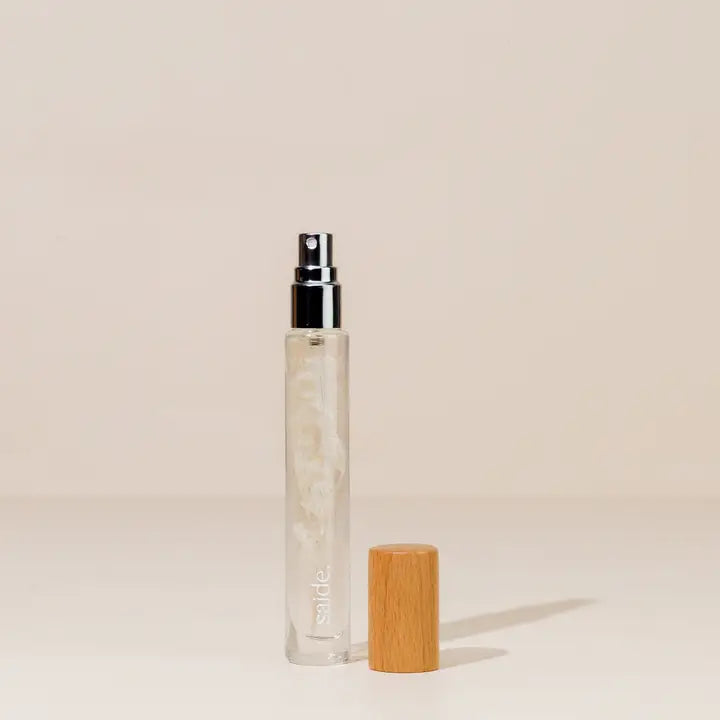 Clear spray parfum bottle with wooden cap on a beige background