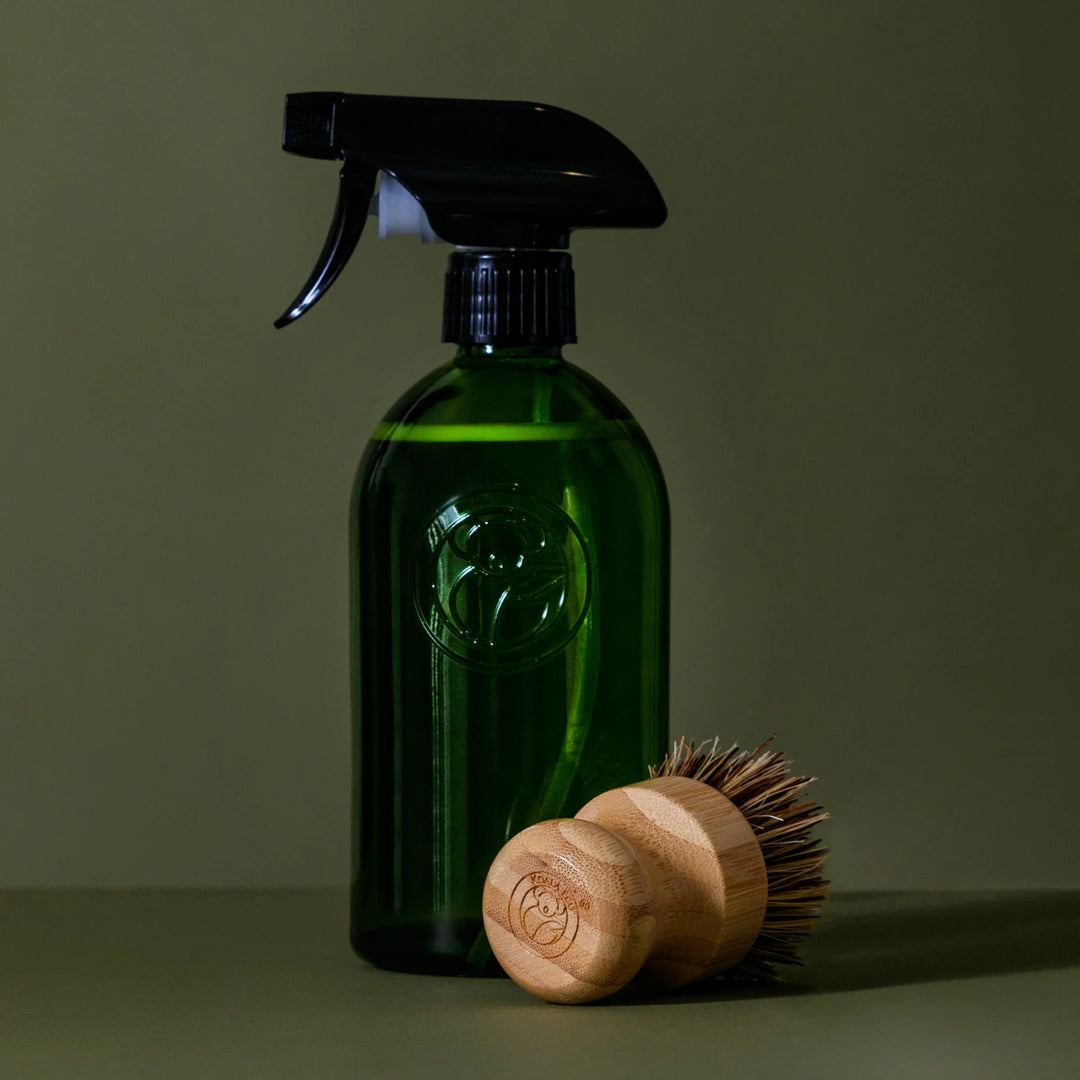 Green spray bottle and wooden brush on a green background
