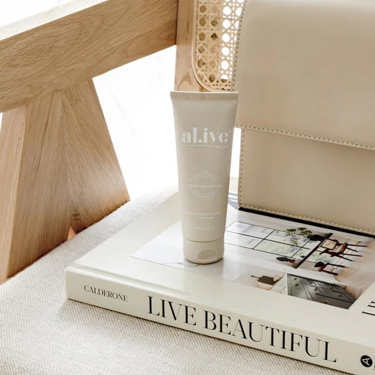 Tube of 'al.ive' cream on a book titled 'Live Beautiful' with a wooden chair in the background.