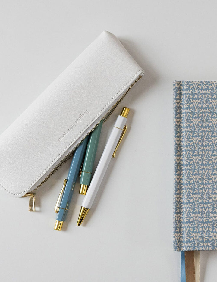 White pouch with pens and a notebook on a light gray background