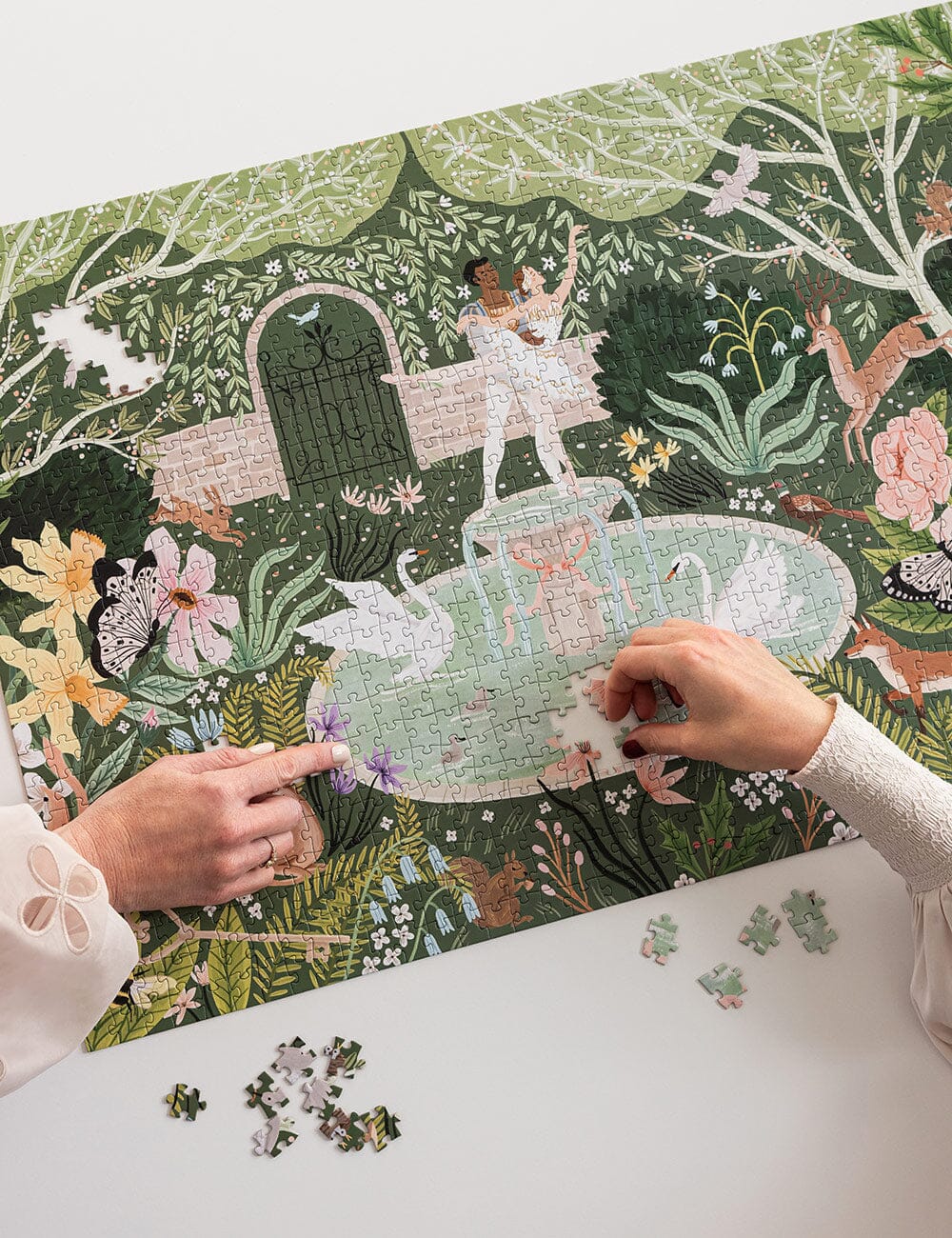 Two people working on a puzzle with a fantasy forest design on a table.