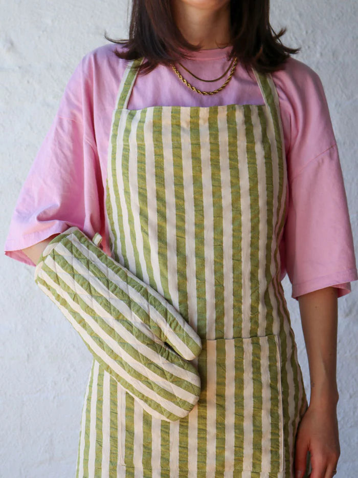 Person wearing a green and white apron with a matching pot mitt