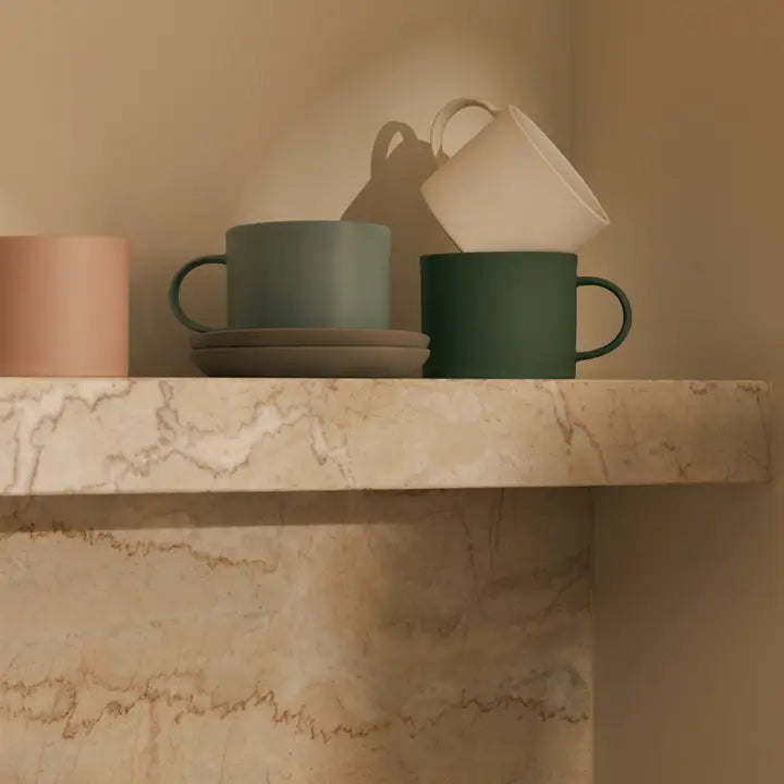 Set of colorful mugs on a marble surface with a neutral background