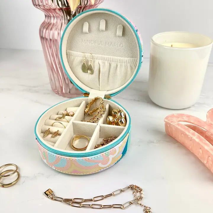 Round jewelry organizer with compartments filled with jewelry on a light surface.