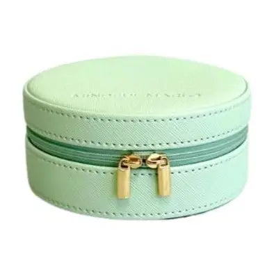 A mint green round jewelry box with a zippered closure and gold-tone hardware, shown on a plain white background.