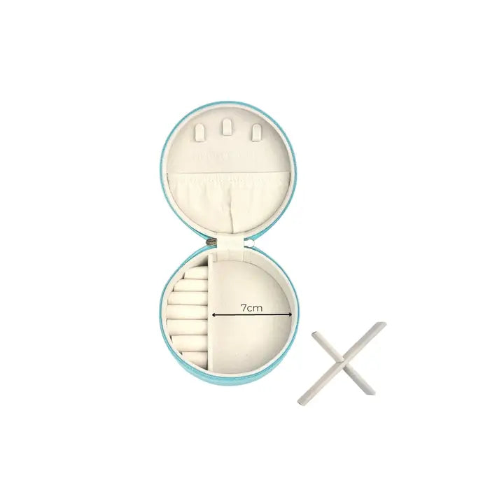 An open round jewelry organizer case with a light blue exterior and cream interior, shown on a white background. The case contains multiple compartments, including a 7cm diameter ring slot area, and a small white cross-shaped accessory is placed to the right.