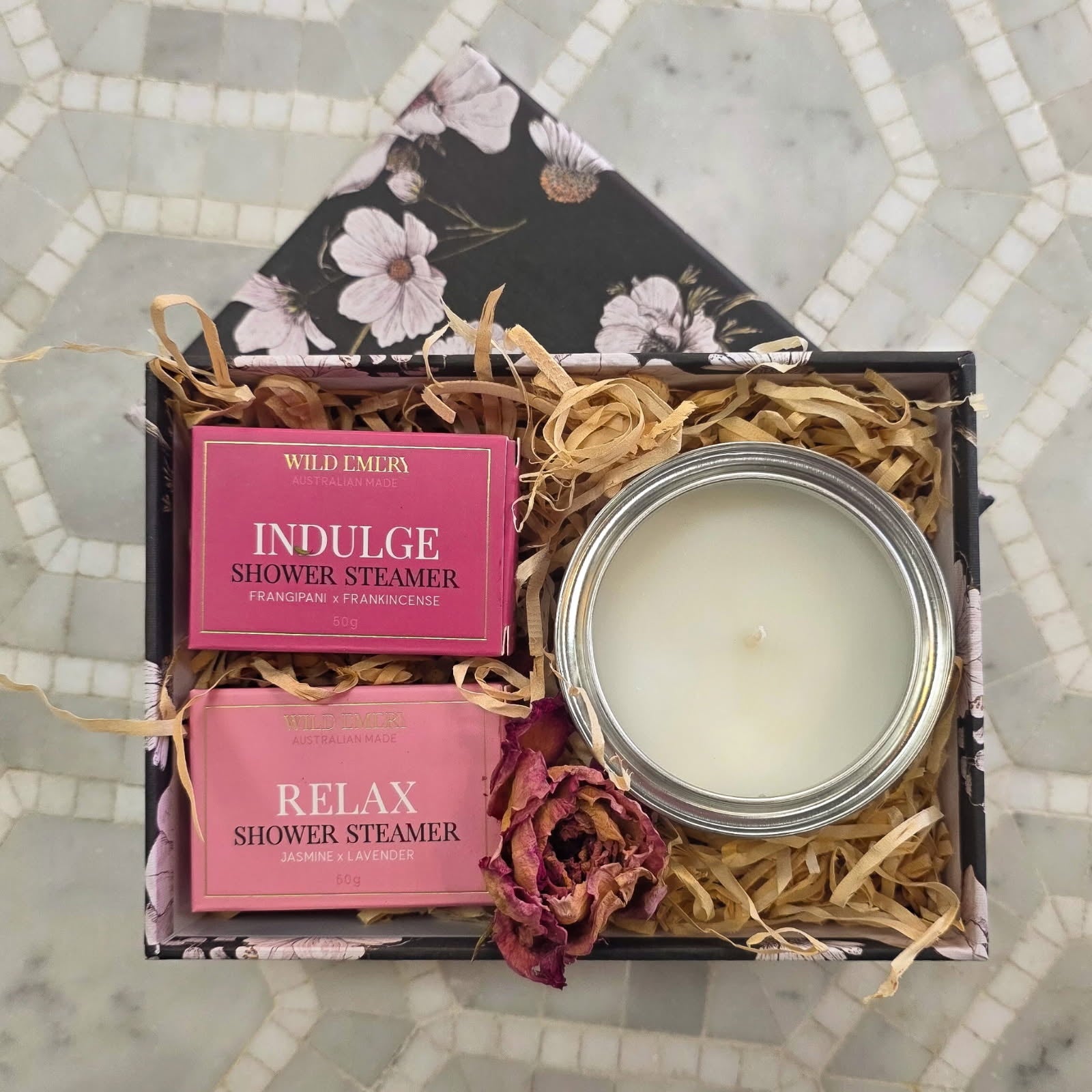 Gift set with shower steamers and a candle on a mosaic tile background