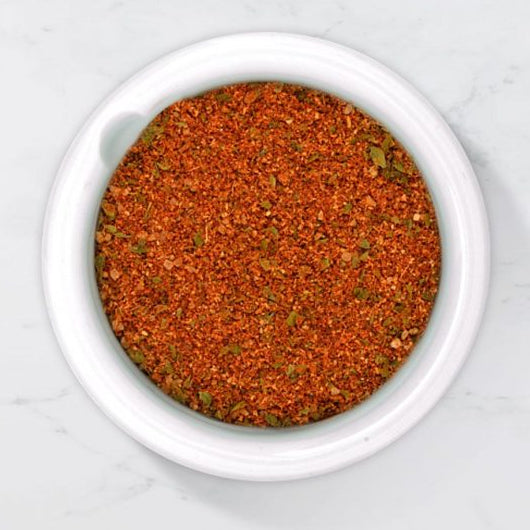 Spice mix of Smokey BBQ spice,  in a white bowl on a light gray background