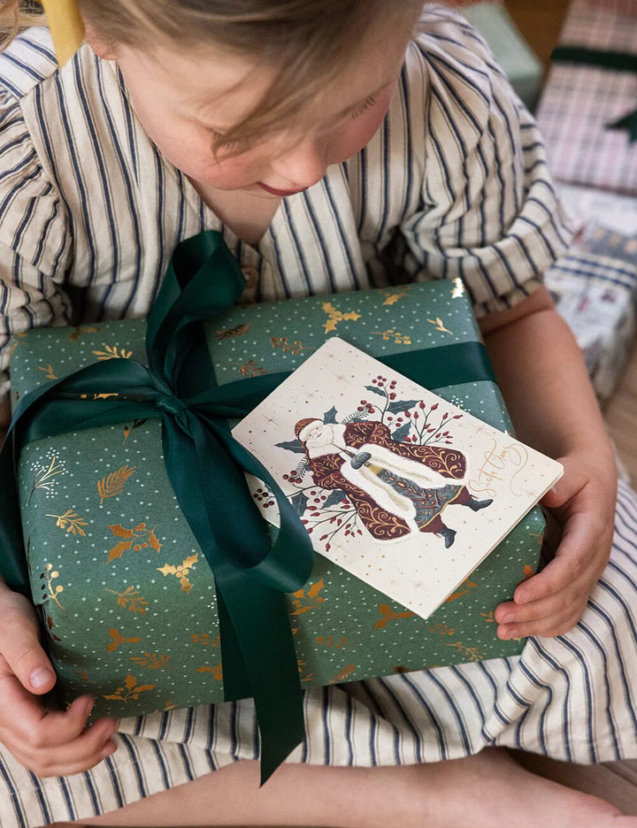 Child holding a wrapped gift with a decorative card