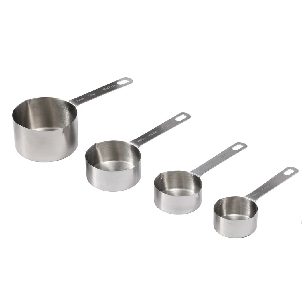 Set of four stainless steel measuring cups on a white background