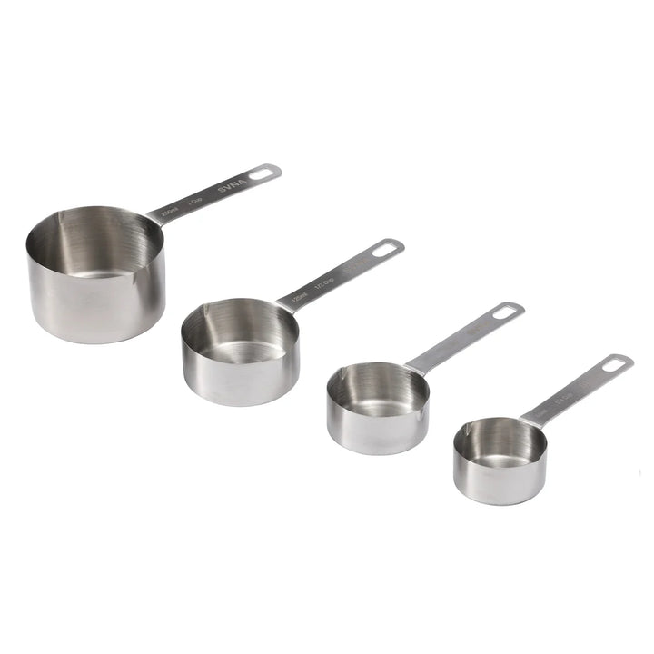 Set of four stainless steel measuring cups on a white background