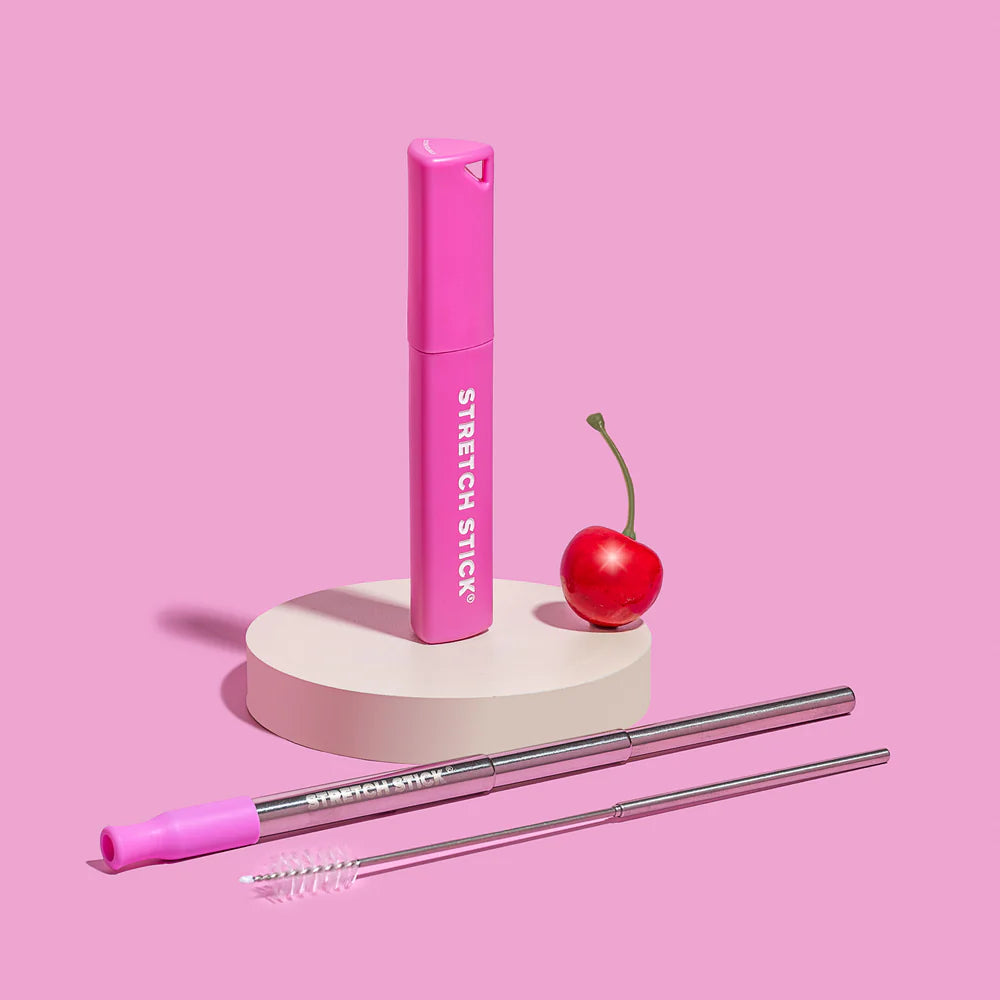 Stretch Me Co reusable cover with a stainless steel straw & cleaning brush on a pink background