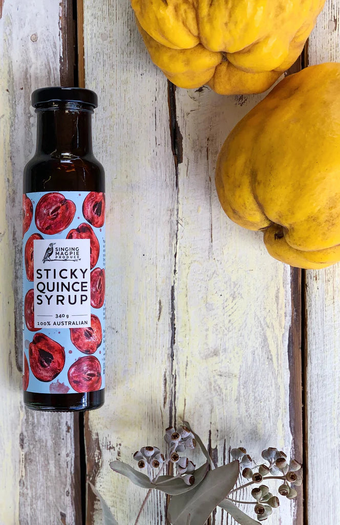 Bottle of Sticky Quince Syrup with quinces on a wooden background