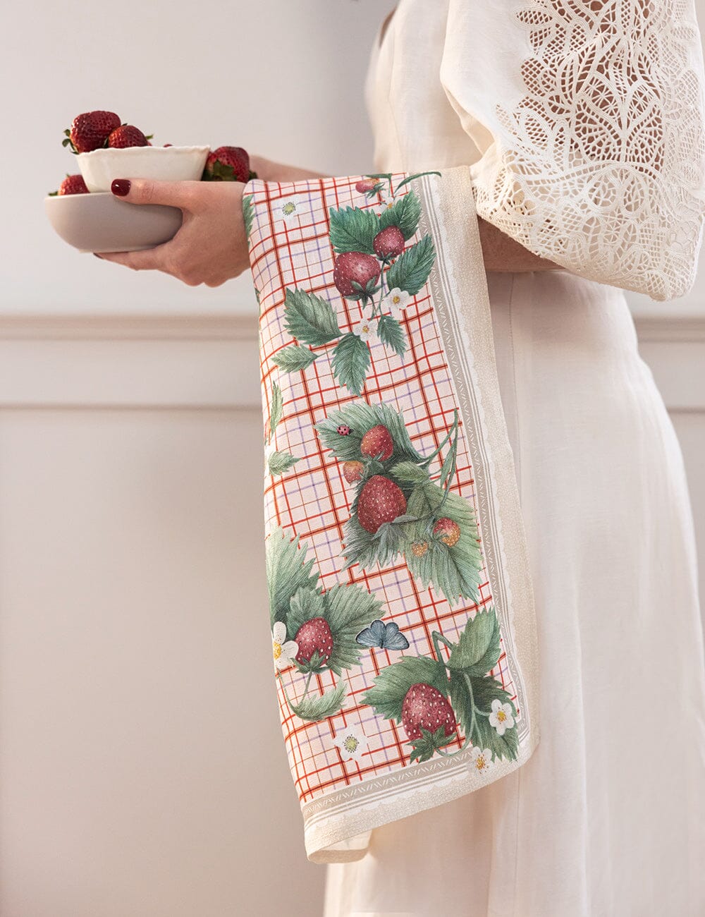 Person holding a towel with strawberry pattern and a bowl of strawberries.