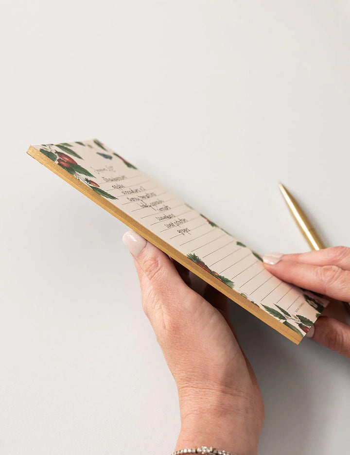 Hand holding a floral notebook with a pen on a light background