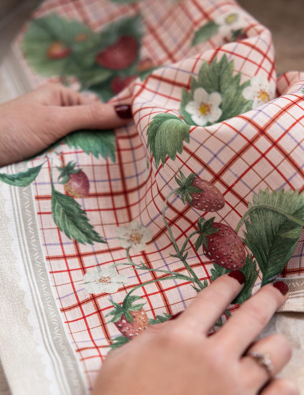 Tea towel with strawberry pattern held by hands