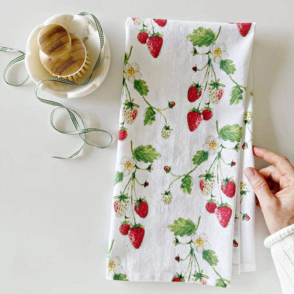 Floral patterned towel with strawberries held by a hand on a light background