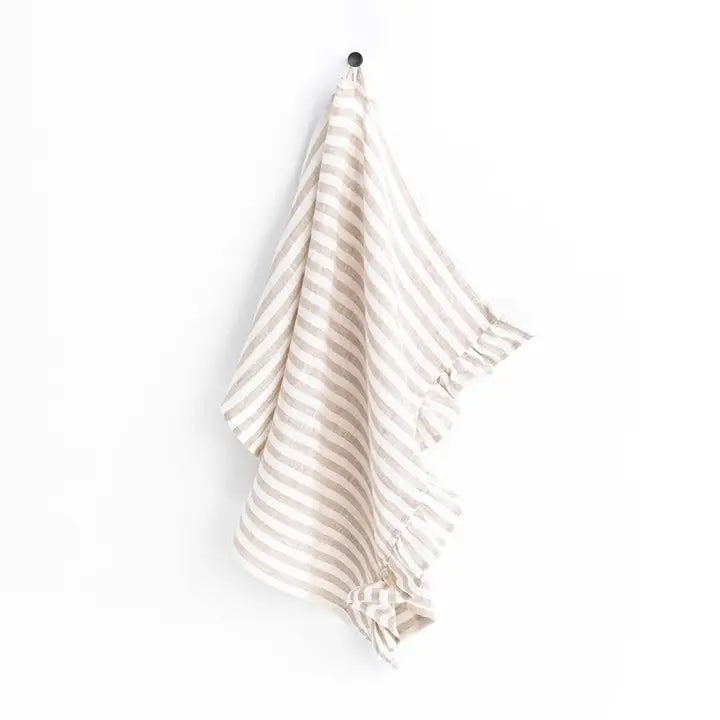 Striped linen tea towel hanging on a hook on a white background