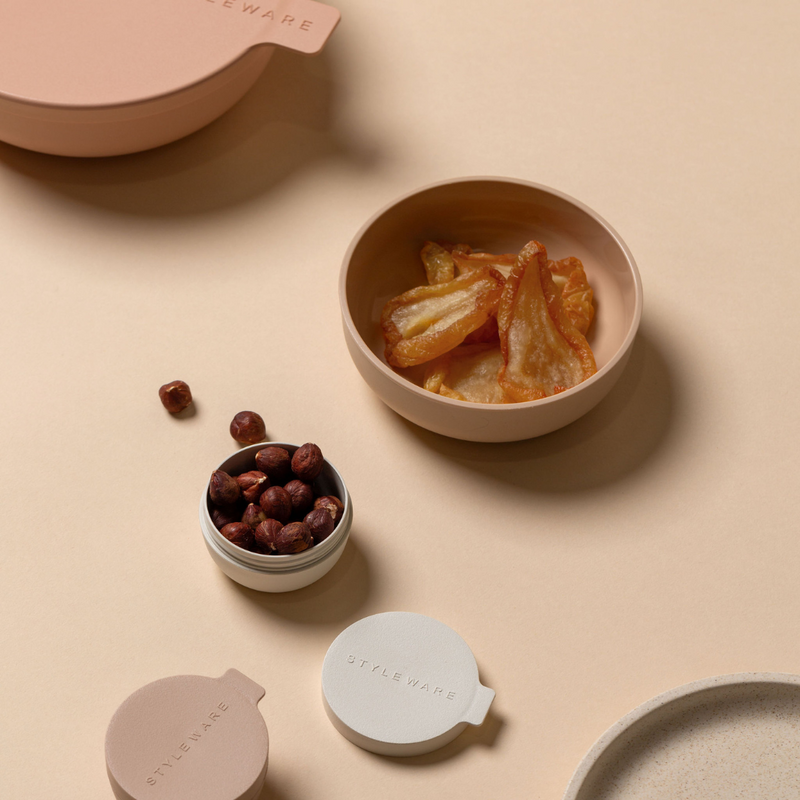 Small bowls with snacks on a beige surface, featuring the brand Styleware