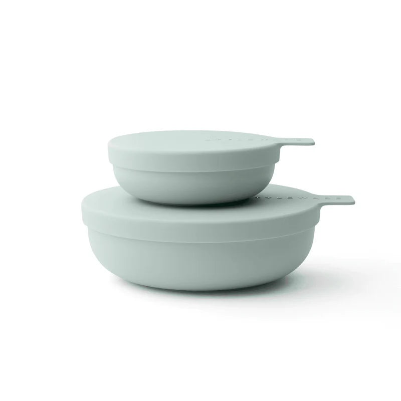Two light green plastic bowls stacked on a white background
