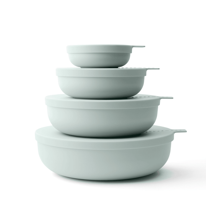 Set of five light green bowls stacked on a white background