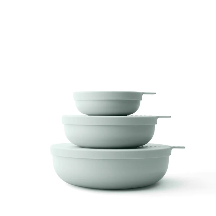 Set of three light green bowls stacked on a white background