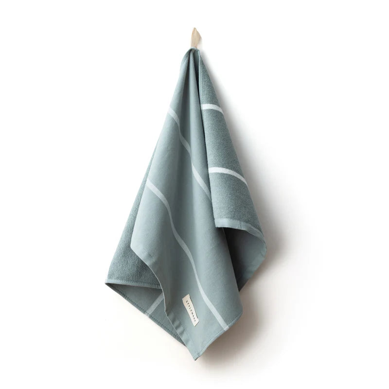 Teal tea towel with white stripes on a wooden hook against a white background