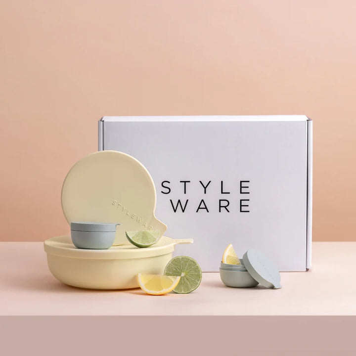 Yellow bowls with small green bowls and lime slices in front of a 'STYLE WARE' box on a pink background