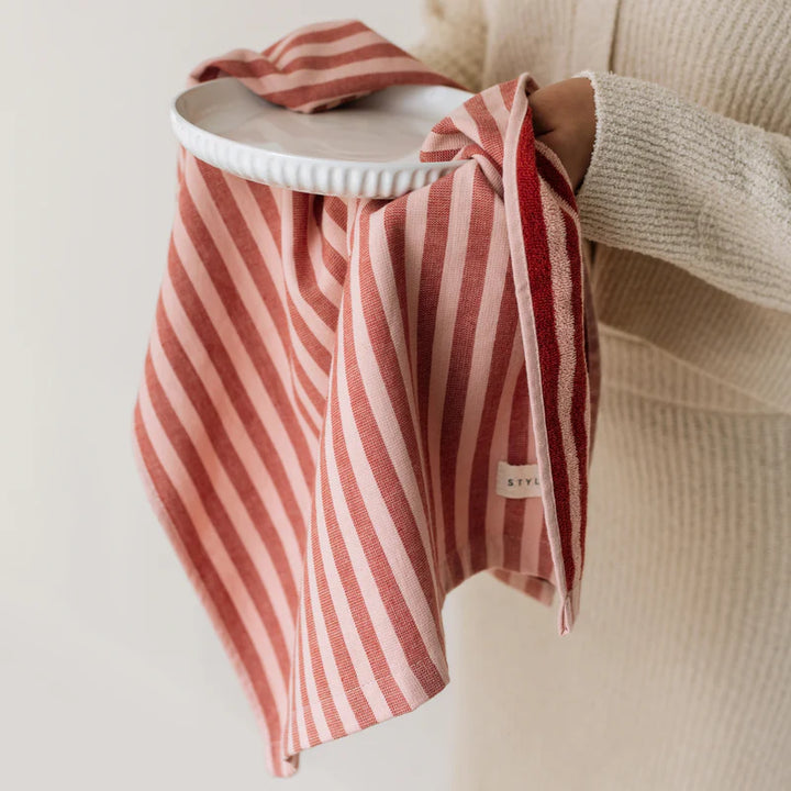 Red and white striped towel draped over a chair with a neutral background