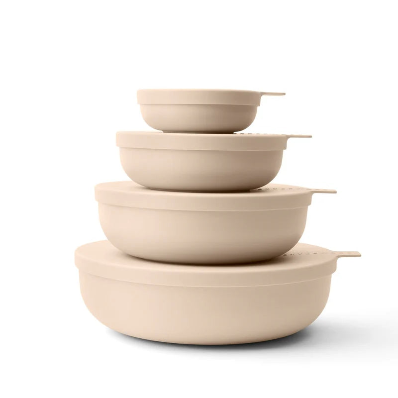 Set of beige plastic bowls & lids stacked on a white background