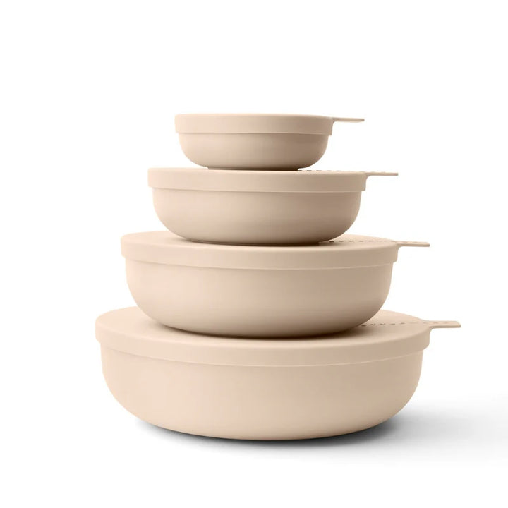 Set of beige plastic bowls & lids stacked on a white background