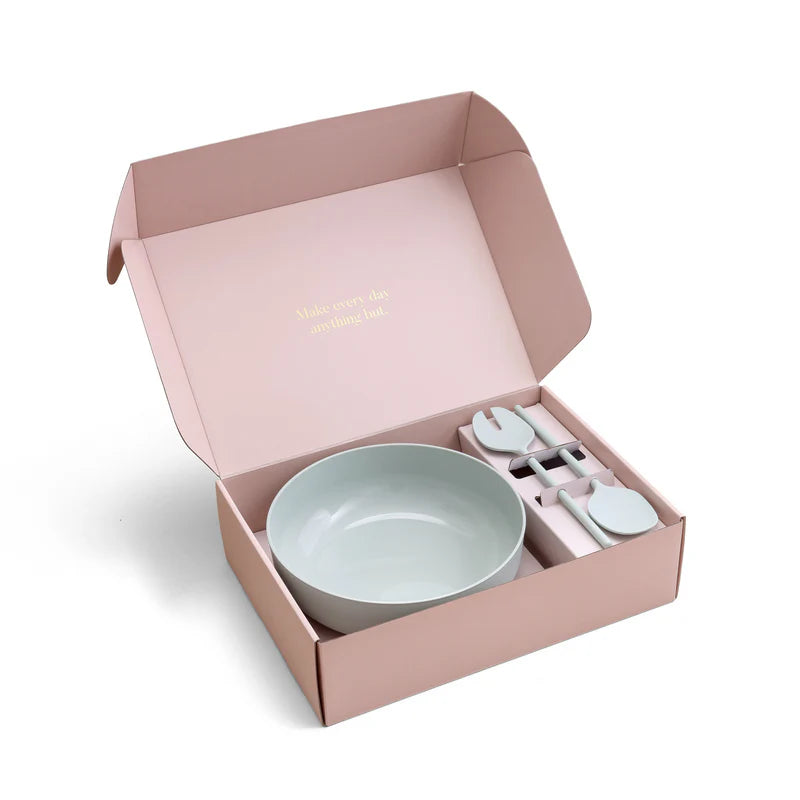 Pink gift box with a green plastic serving bowl and salad server set on a white background