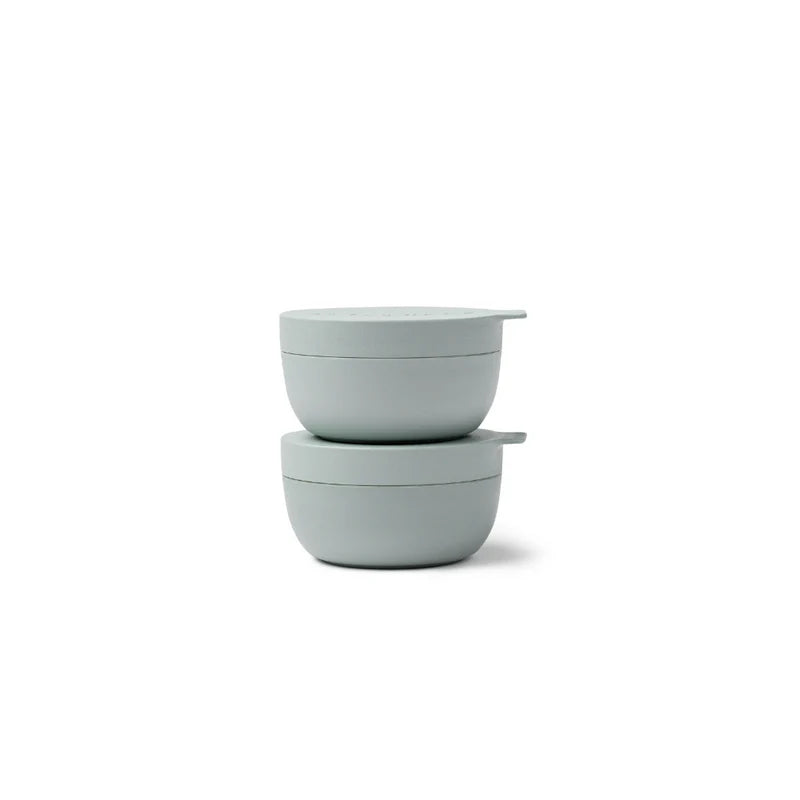 Two light green bowls stacked on a white background