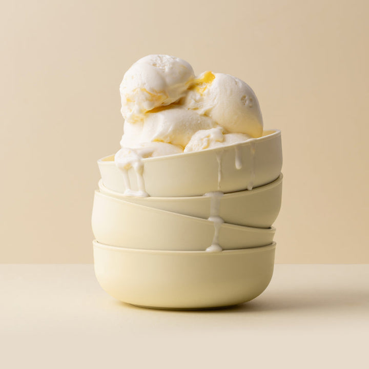 Stack of yellow plastic bowls with ice cream on a beige background