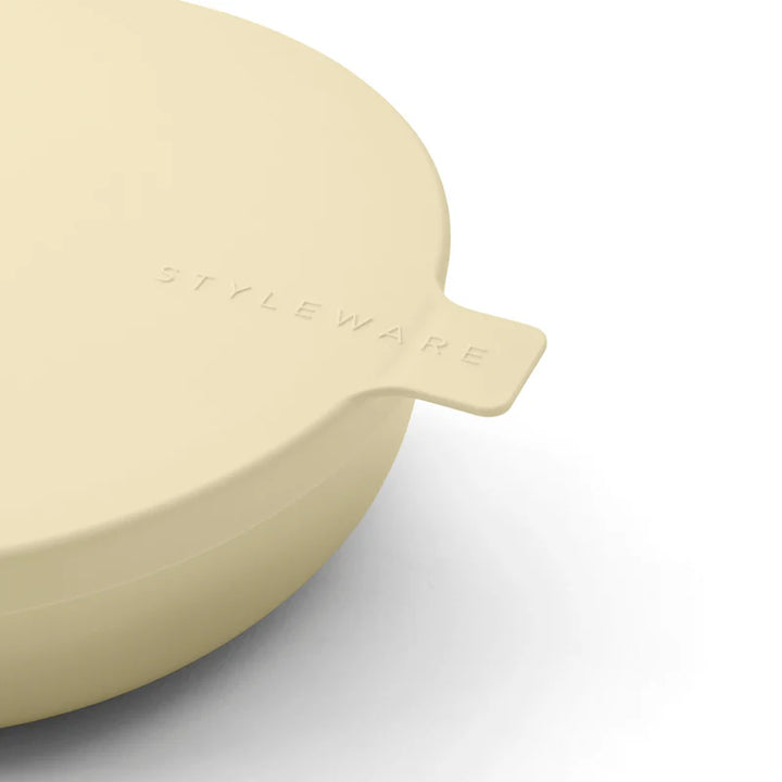 Yellow plastic bowl with 'STYLEWARE' branding on a light gray background