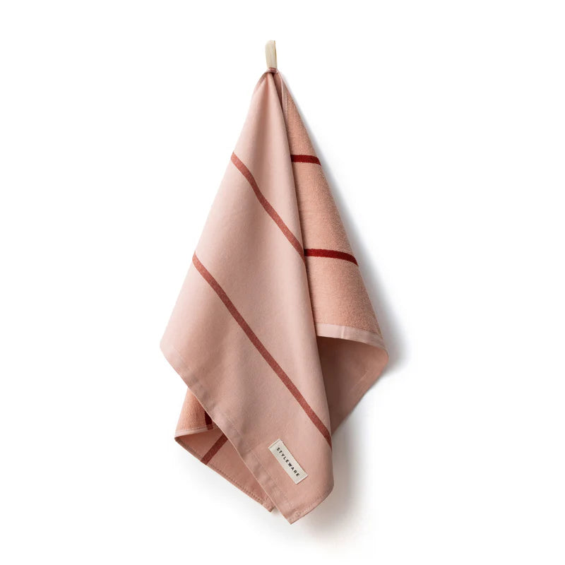 Pink towel with red stripes hanging on a white background