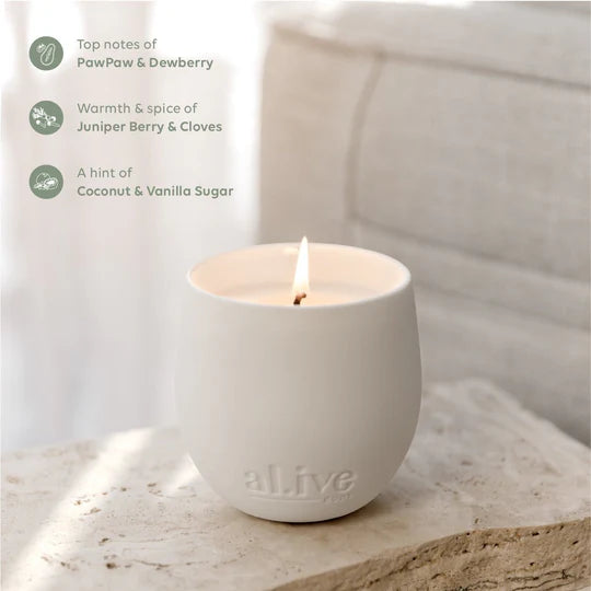 White candle in a ceramic holder with 'allve' branding on a light wooden surface.