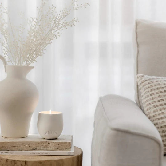 Candle and vase on a table next to a sofa with a neutral color scheme
