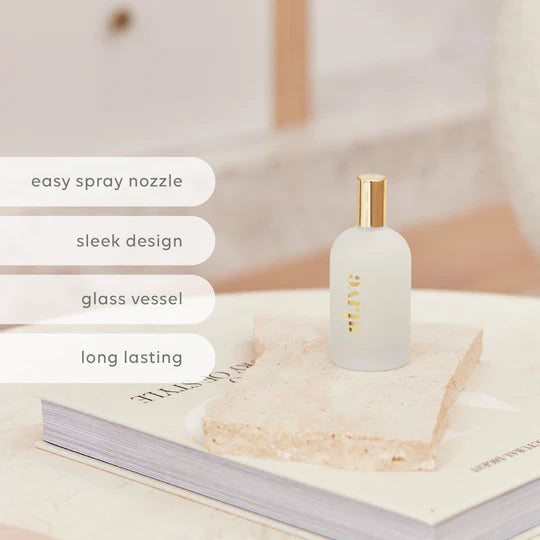 White spray bottle with gold nozzle on a stack of books, featuring text about features.