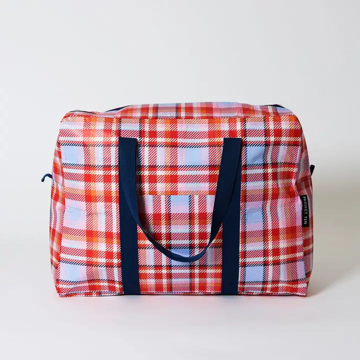 Plaid patterned bag with blue handles on a light gray background