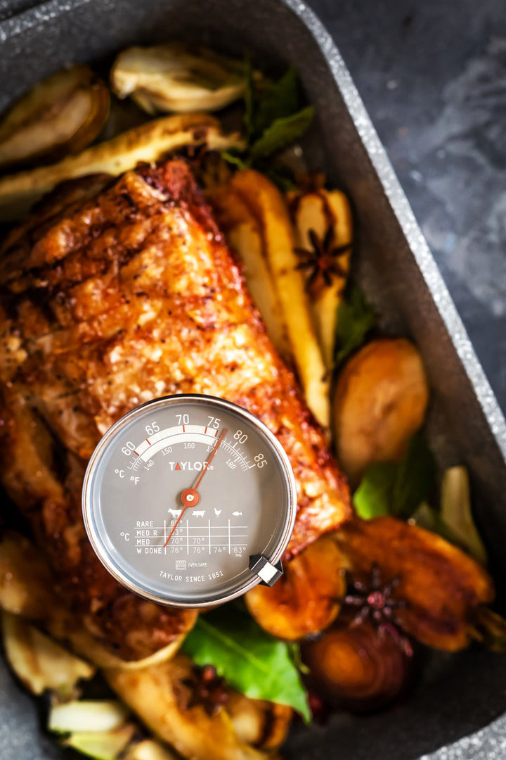 Roasted chicken with vegetables in a pan, featuring a meat thermometer.