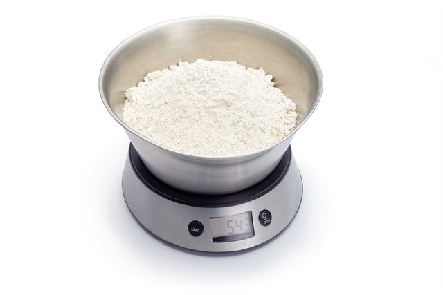 Digital kitchen scale with flour on a white background
