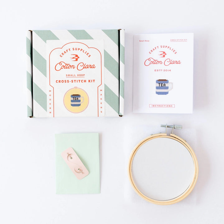 Cotton Clara cross-stitch kit with packaging, hoop, and needle on a white background