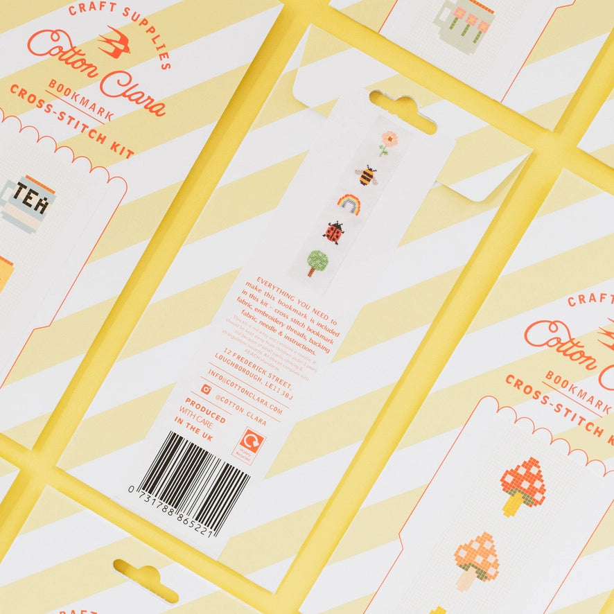 Cross-stitch kit packaging with yellow frames and text on a white background